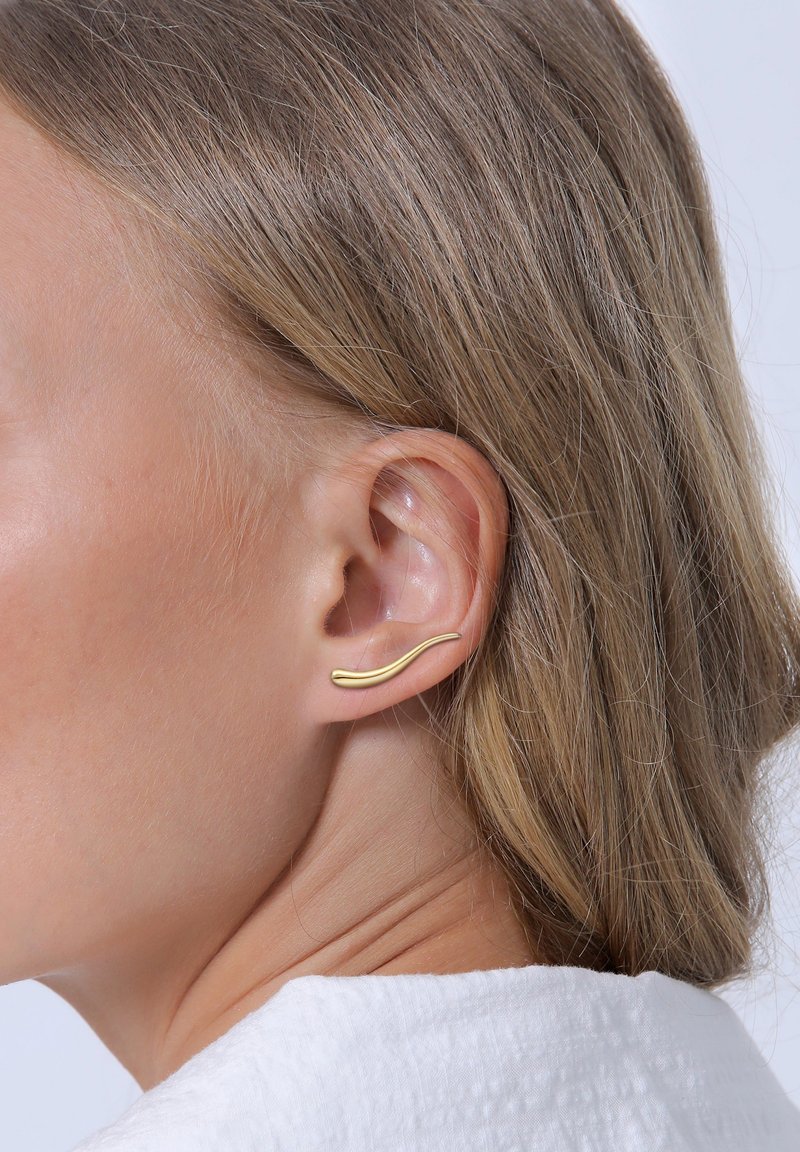 Goldfarbener Ohr-Cuff mit wellenförmigem Design, das entlang des äußeren Ohrs positioniert ist, glatte Textur, minimalistischer Stil und keine sichtbaren Verschlüsse.
