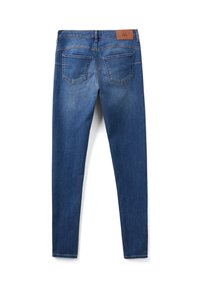 Jeans ajustados en denim azul oscuro, con una textura suave, dos bolsillos traseros y una etiqueta de cuero marrón en la cintura.