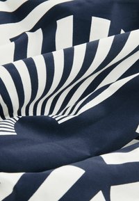 Marinblå och vit mönstrad tyg med växelvis djärva ränder, med en slät struktur och lätt lyster. Designen liknar strålar som utgår från en punkt.