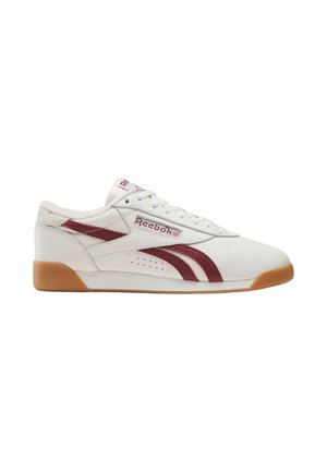 Weißer Reebok-Sneaker mit burgunderfarbenen Logostreifen, Gummisohle und Schnürsenkeln, seitlich gesehen vor weißem Hintergrund.