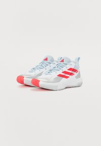 Baskets blanches de sport avec des accents bleu clair, présentant un design à trois bandes rouges, des superpositions texturées en argent et une semelle à motifs.