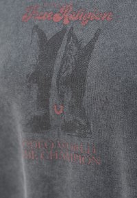 Szara bawełniana koszulka z czarną grafiką kowbojskich butów i czerwonym napisem "True Religion Rodeo World Champion".