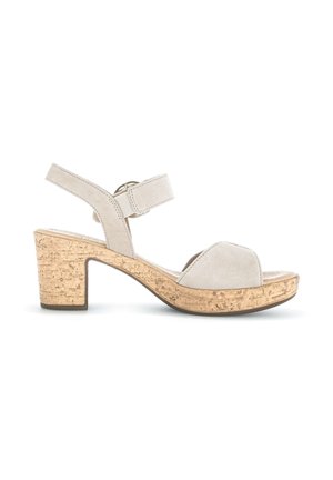 Beige suede open-toe sandal with cork block heel and adjustable ankle strap, side view on white background.