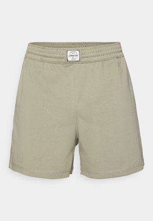 Shorts vert clair en tissu doux, dotés d'une taille élastique avec une étiquette. Design simple sans poches ni motifs.
