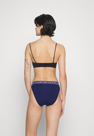 Tumedat sinine puuvillane aluspesu valge logo kummipaela ja musta reguleeritava rihmaga braletiga. Sile tekstuur, sobiv disain.