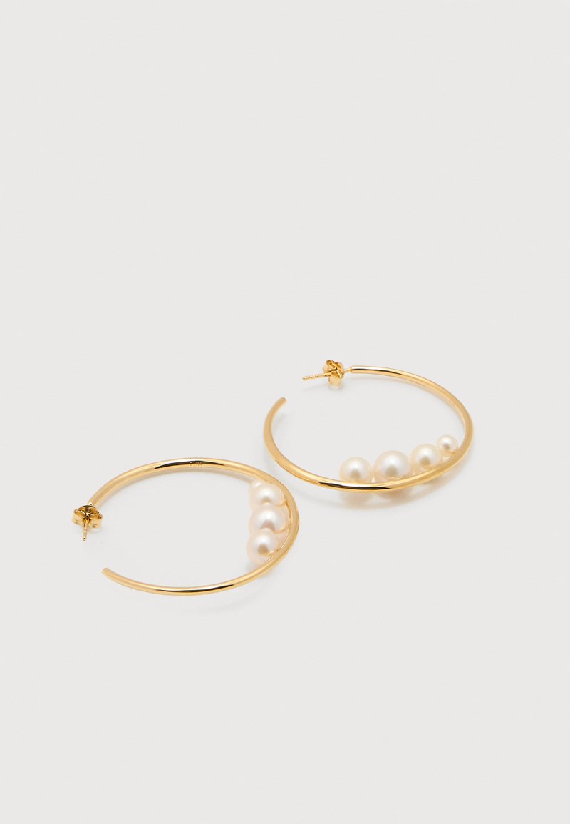 Σκουλαρίκια κρίκοι από χρυσό, το καθένα με πέντε λευκά μαργαριτάρια σε αυξανόμενο μέγεθος κατά μήκος της εσωτερικής καμπύλης, τοποθετημένα σε ένα απλό λευκό φόντο.