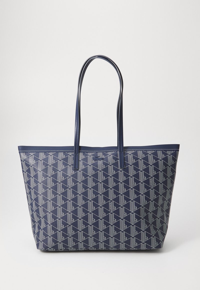 Jūros laivyno spalvos ir geometriniu baltu raštu puošta rankinė, su dviem ilgomis rankenomis, stačiakampio formos ir lygiu sinthetiniu paviršiumi.