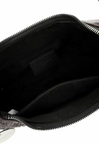 Must nahast koti sisu lukuga, millel on tavaline kangast vooder ja sees väike õmmeldud silt. Täiendavaid taskuid ei ole nähtaval.