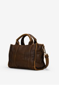 Bolso de mano de cuero marrón con dos asas cortas, una correa de hombro desmontable y detalles cosidos a lo largo de los lados, con una textura suave.