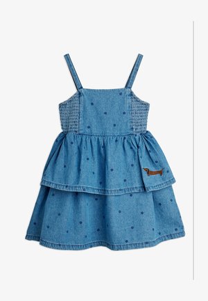 Blue denim sleeveless dress with dark polka dots, smocked sides, tiered skirt, and small embroidered brown dachshund on lower right side.