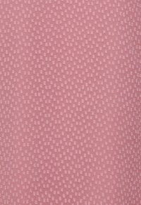 Tessuto rosa con texture che presenta un motivo di piccoli quadrati in rilievo. La superficie mostra una leggera lucentezza e una finitura morbida.