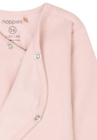 Ljusrosa ribbad inslagstopp för spädbarn, med silverfärgade tryckknappar. Materialet är mjukt med en slät textur, etiketten inkluderar storlek och ursprung.