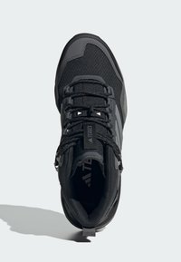 Chaussure de randonnée noire avec une tige en mesh, un col rembourré et des accents gris. Elle dispose de lacets et d'une semelle texturée pour l'adhérence.
