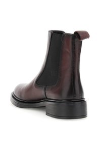 Cizmă Chelsea din piele maro închis cu panou elastic negru pe lateral și buclă de prindere, având un toc scăzut și vârful rotunjit.