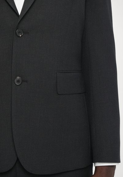 Mørkeblå, tætsiddende blazer lavet af tekstureret stof med to sorte knapper, en slank brystlomme og en renlinet krave.