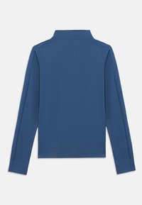 Πόλο μπλούζα με μακριά μανίκια σε μονόχρωμο μπλε χρώμα. Διαθέτει γιακά, ίσια ραφή στο κάτω μέρος και απαλό, ελαφρύ ύφασμα. Χωρίς ορατά σχέδια ή διακοσμητικά στοιχεία.