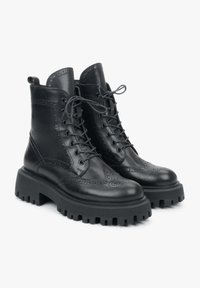 Czarne skórzane botki do kostki z wzorem wingtips, okrągłym przodem, sznurowanym z przodu oraz masywną gumową podeszwą z głębokim wzorem dla lepszej przyczepności.