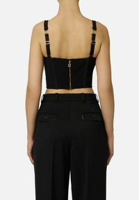 Top noir court avec bretelles réglables, doté d'une fermeture éclair métallique à l'arrière. Associé à un pantalon noir taille haute avec poches à rabat.