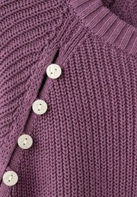 Pull tricoté violet avec une texture côtelée, comprenant cinq boutons ronds de couleur claire le long du côté pour la fermeture.