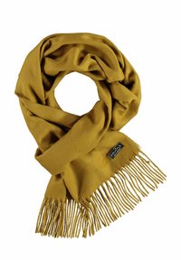 Sciarpa giallo senape realizzata in morbido materiale, con bordi frangiati e un piccolo etichetta del marchio. Il design è semplice e accogliente.