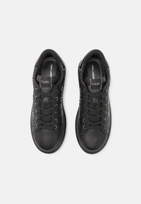 Zwarte leren sneakers met een gladde afwerking, platte veters en reliëflogo-details aan de zijkanten. Ronde neus en gepolsterde kraag.