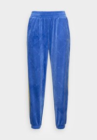 Blå velourbyxor med elastisk midjeband, med en diamantdesign och gula sidostråkar. Bensluten är elastiska för en tight passform.