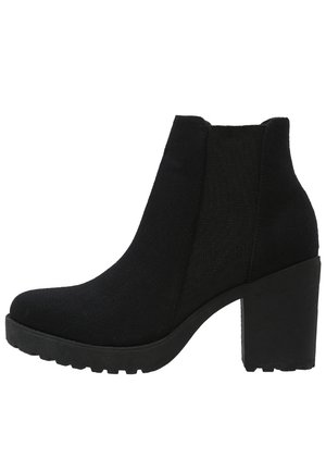 Schwarzer Wildleder-Stiefelette mit klobigem Absatz, elastischem Seitenteil und profilierter Sohle, seitlich auf weißem Hintergrund dargestellt.