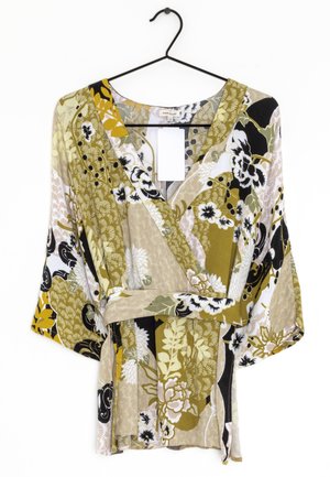 Floral print wrap blouse featuring green, black, and beige hues. Made of lightweight fabric with wide sleeves and a belted waist detail.