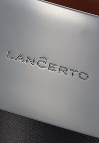 Srebrna metalowa powierzchnia z wytłoczonym napisem "LANCERTO." Poniżej znajduje się teksturowany czarny materiał, prawdopodobnie skóra. Gładki, elegancki design.