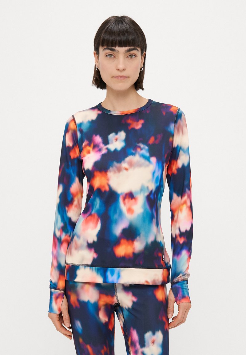 Top de desporto de manga longa feito em tecido elástico com um padrão abstrato multicolor em azul, rosa e laranja. Apresenta um decote redondo e buracos para os polegares.