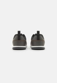 Chaussures gris foncé avec une tige lisse, des panneaux en mesh, une semelle intermédiaire blanche et une semelle extérieure noire. Dotées d'une languette pour un enfilage facile.