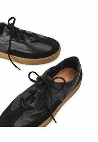 Zapatos de cuero negro con acentos de ante, punta redonda y cordones negros. Presentan una suela de goma y un acabado texturizado en la parte superior.