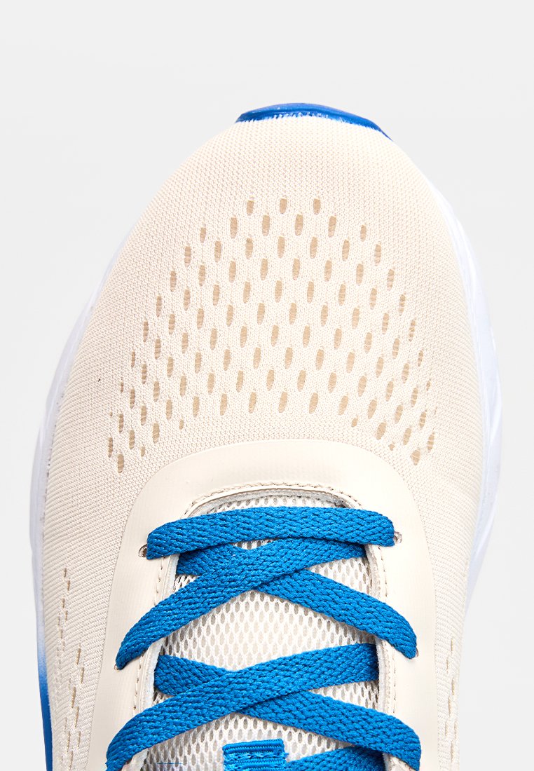 Beige Mesh-Sneaker mit perforiertem Obermaterial, blauen Schnürsenkeln und weißer Sohle; verfügt über eine strukturierte Oberfläche und glatte Akzente entlang der Kanten.