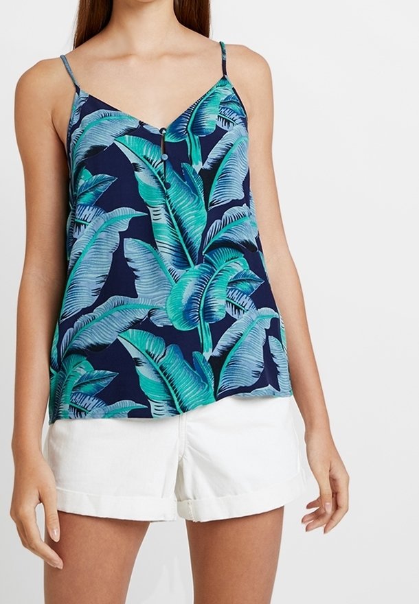 Blå linne med tropiskt bladmönster i gröna toner. Har justerbara spaghettiband och en knappdetalj vid halsringningen.