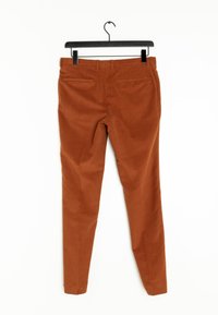 Gebrande oranje, slim-fit broeken met een gladde textuur, twee achterzakken en een tailleband op een zwartehanger tegen een witte achtergrond.