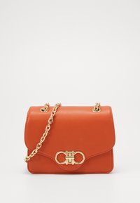 Borsa a tracolla in similpelle arancione con una catena dorata, chiusura a patta e un accentuato dettaglio in metallo dorato sul davanti.