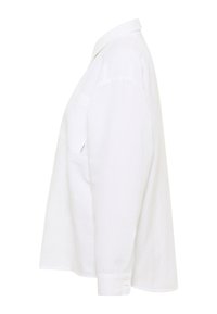 Biała lniana koszula o miękkiej fakturze, z długimi rękawami, boczną kieszenią, zapinanymi mankietami i klasycznym kołnierzykiem. Widok z boku ukazuje luźny krój.