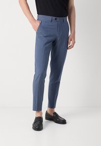 Ljust blå skräddarsydda byxor med en slät yta, slim fit och framfickor. Återfinns i kombination med svarta läder loafers.
