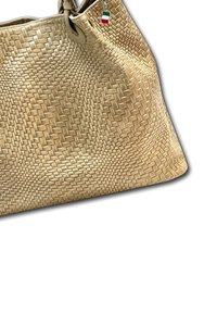 Geweven beige handtas met een textured patroon en een charm van de kleine Italiaanse vlag die aan de handgreep hangt, tegen een witte achtergrond.