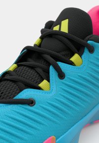 Athletic shoe with a turquoise upper, textured black mesh tongue, black laces, lime green accents, and pink rubber sole details.