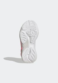 White rubber shoe sole featuring a textured grip pattern, with pink accents and a prominent logo. Curved shape, lightweight design.