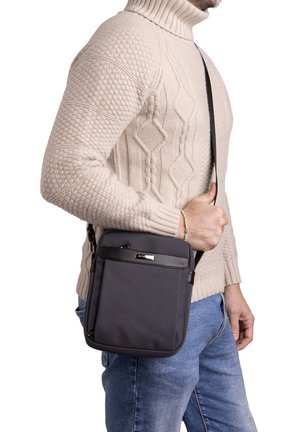 Grijze crossbody tas van textuurstof, verstelbare schouderriem, voorvak met rits en slanke zwarte accenten. Compact ontwerp geschikt voor dagelijks gebruik.