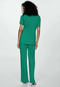 Teal twee-delige outfit met een ribbelachtige top met korte mouwen en bijpassende brede broek met een gladde textuur en een losse pasvorm.