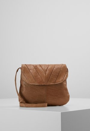 Small brown leather wristlet bag with a curved flap and stitched chevron pattern on a white surface against a plain gray background.