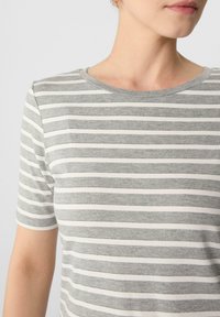 Graues und weißes gestreiftes T-Shirt mit Rundhalsausschnitt und kurzen Ärmeln. Der Stoff scheint weich und leicht zu sein. Schlichtes Design mit horizontalen Streifen.