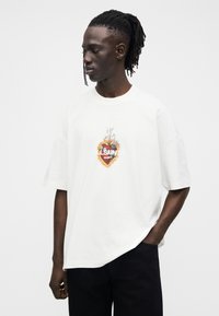 White oversized t-shirt made from cotton, featuring a colorful graphic print at the center with "ALLSAINTS" text and floral design.