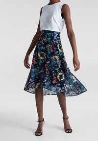 Blommig midi kjol med marinblå bakgrund, färgglad blommönster; tillsammans med en vit ärmlös topp. Slätt tyg med en flödande form.