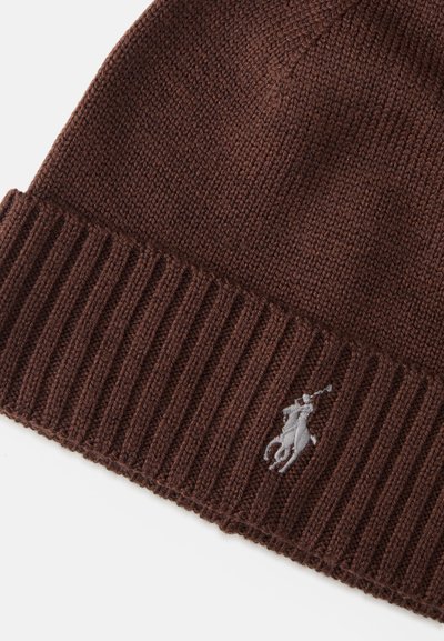 Gorro de malha castanho com punho canelado. Apresenta um pequeno logo bordado em cinza claro. Textura suave e design de topo arredondado.