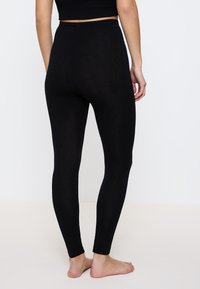 Zwarte legging met een hoge taille, een soepele textuur en een aansluitende pasvorm. Geen zichtbare naden, ontworpen voor comfort en flexibiliteit.