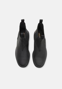 Bottes de cheville en cuir noir au design épuré, dotées de panneaux élastiques sur les côtés et de tirettes pour un enfilage facile. Semelle plate avec un matériel minimal.